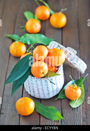 frische Mandarinen in den weißen Korb und auf einem Tisch Stockfoto