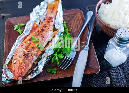gebackener Fisch in der Folie und auf einem Tisch Stockfoto