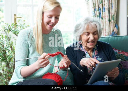Großmutter mit Digital-Tablette während Enkelin strickt Stockfoto