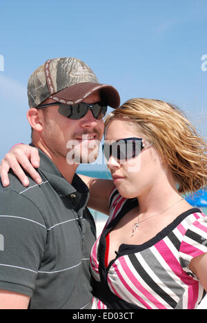 Junges Paar draußen am Strand.  Beide haben auf Sonnenbrille. Stockfoto
