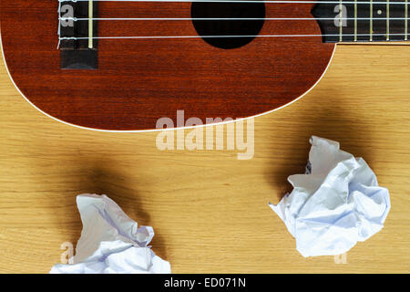 Ukulele Gitarre mit Papierfetzen auf Holz Stockfoto