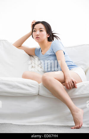 Junge Frau sitzt auf dem sofa Stockfoto
