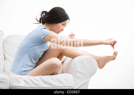 Junge Frau, die ihre Fußnägel Lackieren Stockfoto