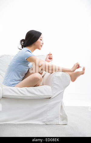 Junge Frau, die ihre Fußnägel Lackieren Stockfoto