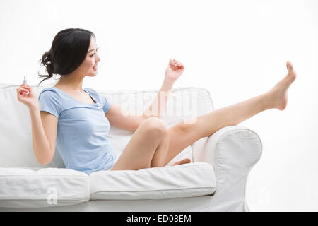 Junge Frau, die ihre Fußnägel Lackieren Stockfoto