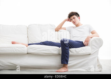 Junger Mann denken auf couch Stockfoto