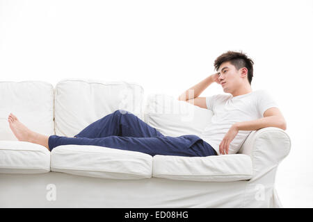 Junger Mann denken auf couch Stockfoto