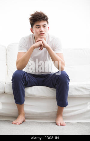 Junger Mann denken auf couch Stockfoto