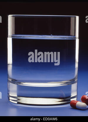 Still-Leben. Kapseln Tabletten neben einem Glas Wasser. Stockfoto