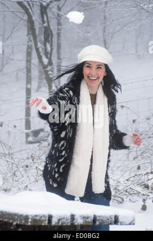Frau trägt Strick genießen Schnee, Schneeball werfen Stockfoto