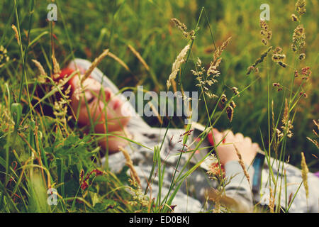 Junge Frau, die ein Buch im Gras liegend hält und schläft Stockfoto