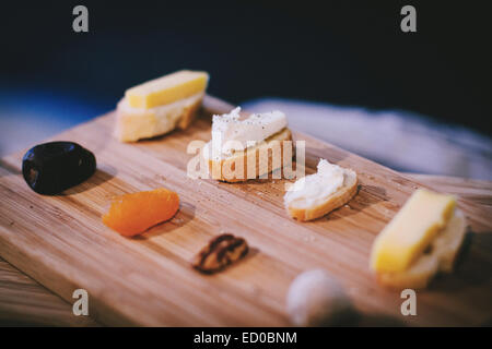 Brot und Käse mit getrockneten Früchten und Nüssen auf einem Schneidebrett Stockfoto