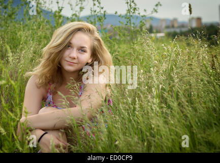 Porträt von Teenager-Mädchen (14-15) sitzen im Feld Stockfoto