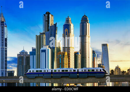 Blick auf moderne Gebäude mit u-Bahn bei Sonnenuntergang in der Dubai Marina, Dubai Stockfoto