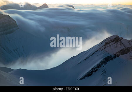 Dies ist ein Sonnenaufgang in den Bergen des Kaukasus (Georgien, Gudauri). Wolken bedeckten Gipfeln und und kriechen über die Bergkette. Stockfoto