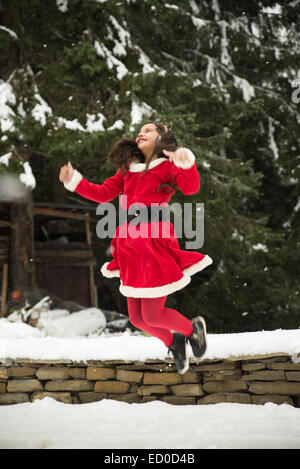 Mädchen mit Weihnachten Santa Outfit in die Luft springen Stockfoto