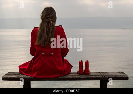 Mädchen auf Bank sitzen und auf dem Meer suchen Stockfoto