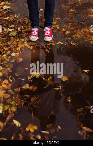 Frau stehend durch Pfütze im Herbst park Stockfoto