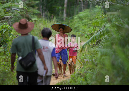 Eine Frau mit einem Kind und Hunden, die auf einem ländlichen Weg gehen und während einer Ökotourismus-Bewertung in entgegengesetzter Richtung zu Männern reisen. Stockfoto