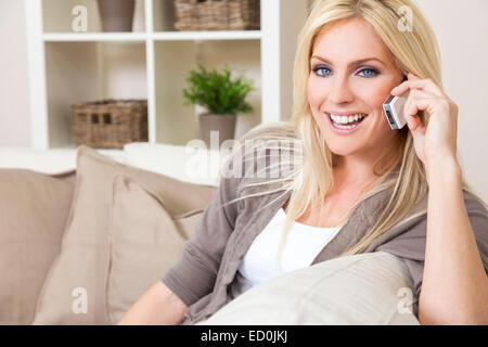 Eine schöne junge Frau reden über ihr Handy zu Hause Stockfoto