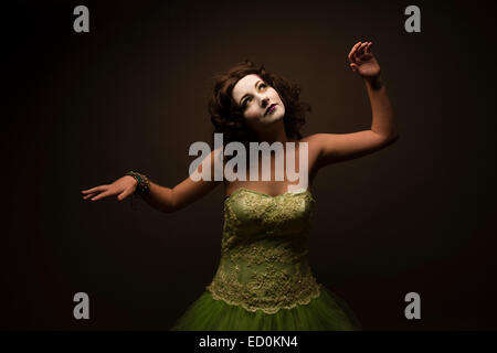 Fantasy-Makeover-Fotografie: eine junge Frau-Mädchen-Modell gebildet um zu schauen wie White-faced bemalte Puppe Porzellan und posiert wie eine lebensechte Puppe in einem Fotostudio tragen eine große grüne Kleid Kleid Ballkleid Stockfoto
