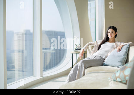 Glückliche junge Frau sitzt auf dem sofa Stockfoto