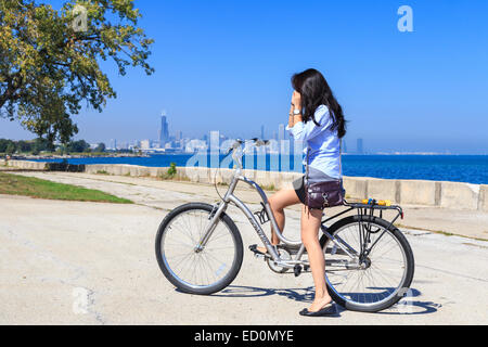 Mädchen auf dem Fahrrad vor der Ferne Skyline von Chicago am Lake Michigan. Stockfoto