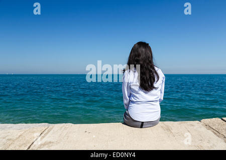 Junge asiatische Frau sitzt an einem sonnigen Tag am Lake Michigan im Parkbereich Hyde von Chicago, IL, USA. Stockfoto