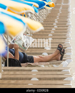 Mann liest Zeitung auf der Sonnenliege am Strand in Spanien Stockfoto