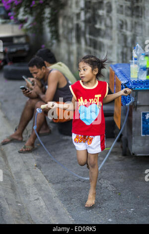 Bangkok, Bangkok, Thailand. 23. Dezember 2014. BAI THONG, 7 Jahre alt, springt Seil vor dem Training in der Turnhalle der Kanisorn in Bangkok. Sie hat etwa 5 Monate lang geboxt. Die Kanisorn-Box-Gym gibt einen kleinen Fitnessraum entlang der Wong Wian Yai - Samut Sakhon Bahngleisen. Junge Menschen aus den umliegenden Gemeinden kommen in die Turnhalle, Thai-Boxen zu lernen. Muay Thai (Muai Thai) ist eine gemischte Kampfkunst in Thailand entwickelt. Muay Thai wurde international im zwanzigsten Jahrhundert, als Thai-Boxer andere bekannte Boxer besiegt weit verbreitet. Eine professionelle Liga richtet sich nach der World Muay Thai Council. MUA Stockfoto