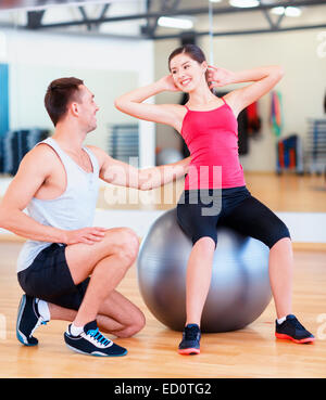 männlichen Trainer mit Frau Crunches auf dem ball zu tun Stockfoto