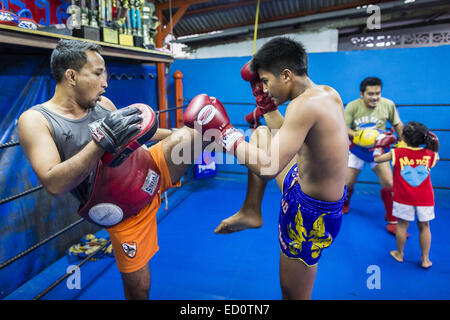 Bangkok, Bangkok, Thailand. 23. Dezember 2014. Boxer-Spar und Training in der Turnhalle der Kanisorn in Bangkok. Die Kanisorn-Box-Gym gibt einen kleinen Fitnessraum entlang der Wong Wian Yai - Samut Sakhon Bahngleisen. Junge Menschen aus den umliegenden Gemeinden kommen in die Turnhalle, Thai-Boxen zu lernen. Muay Thai (Muai Thai) ist eine gemischte Kampfkunst in Thailand entwickelt. Muay Thai wurde international im zwanzigsten Jahrhundert, als Thai-Boxer andere bekannte Boxer besiegt weit verbreitet. Eine professionelle Liga richtet sich nach der World Muay Thai Council. Muay Thai gilt häufig als Weg aus der Armut für junge Thais. MUA Stockfoto