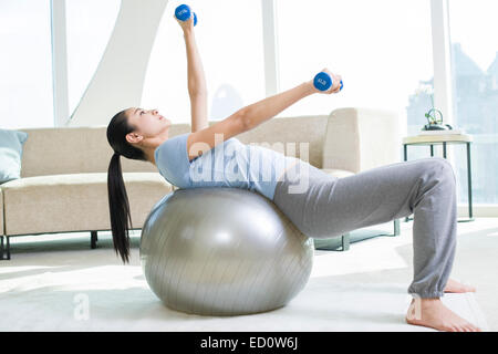 Junge Frau, die das Training mit Hanteln und Fitness-ball Stockfoto