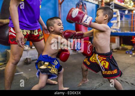 Bangkok, Thailand. 23. Dezember 2014. Junge Burschen Holm auf den Boden der Kanisorn Turnhalle. Die Kanisorn-Box-Gym gibt einen kleinen Fitnessraum entlang der Wong Wian Yai - Samut Sakhon Bahngleisen. Junge Menschen aus den umliegenden Gemeinden kommen in die Turnhalle, Thai-Boxen zu lernen. Muay Thai (Muai Thai) ist eine gemischte Kampfkunst in Thailand, die International im 20. Jahrhundert weit verbreitet als Thai-Boxer andere bekannte Boxer besiegt entwickelt. Eine professionelle Liga richtet sich nach der World Muay Thai Council. Muay Thai gilt häufig als Weg aus der Armut für junge Thais. Stockfoto