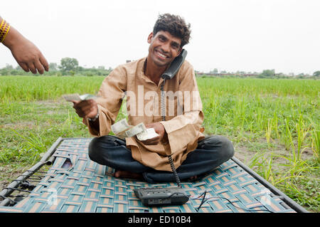 1 indische ländliche Landwirt Telefon reden und geben Geld Stockfoto