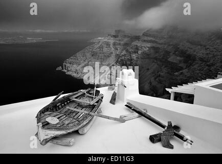 Santorini, Griechenland. Ein altes Boot auf dem Dach eines Hauses in Firostefani Dorf, schwebt über der Caldera. Stockfoto