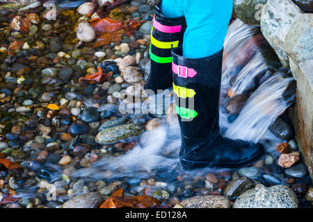 Junger Mensch in Latex Stiefel spielen in einem stream Stockfoto