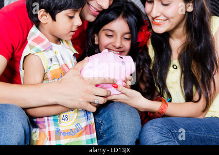 indischen Eltern mit Kindern Piggy Bank Geld sparen Stockfoto