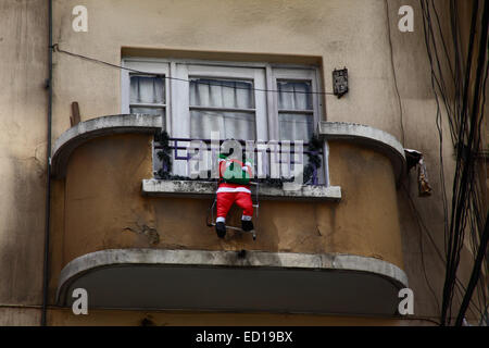 La Paz, Bolivien. 23. Dezember 2014. Aufblasbare Figur des Weihnachtsmanns hängen von Ihrem Balkon aus beim Klettern auf einen Multi-Etagen-Wohnung im Zentrum Stadt. Bildnachweis: James Brunker / Alamy Live News Stockfoto