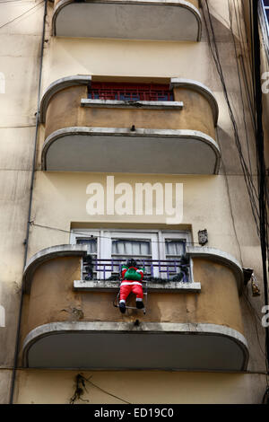 La Paz, Bolivien. 23. Dezember 2014. Aufblasbare Figur des Weihnachtsmanns hängen von Ihrem Balkon aus beim Klettern auf einen Multi-Etagen-Wohnung im Zentrum Stadt. Bildnachweis: James Brunker / Alamy Live News Stockfoto