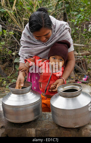 Frau des Stammes der Rathwa ihres Kindes Händewaschen, Gujarat, Indien Stockfoto