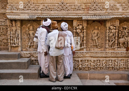 Gujarati Männer bewundern kunstvolle Schnitzereien an Wand von Rani-Ki-Vav Schritt gut, Patan, Gujarat, Indien Stockfoto