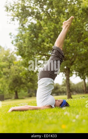 Konzentrierte Brünette beim Yoga auf Rasen Stockfoto