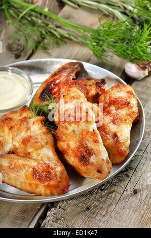 Gebratene Hähnchenflügel mit Sauce auf rustikalen Tisch Stockfoto