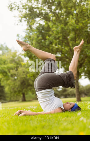 Konzentrierte braune Haare tun Yoga auf Rasen Stockfoto