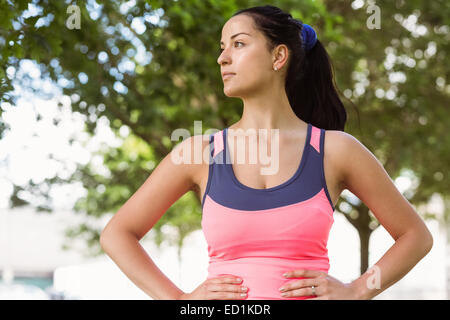 Fit Brünette lächelnd mit Hände auf den Hüften Stockfoto