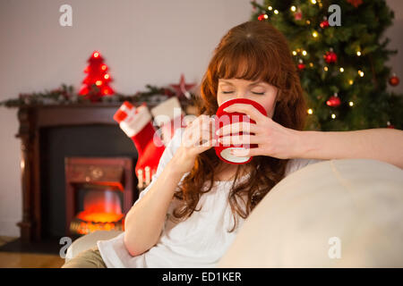 Hübsche Rothaarige auf Couch trinken heißen Schokolade Stockfoto