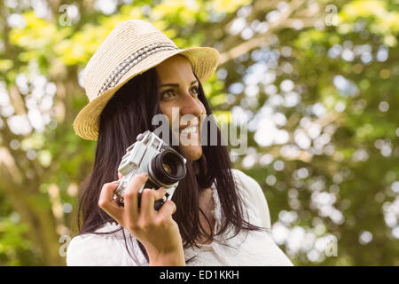 Lächelnde Brünette im Strohhut mit Retro-Kamera Stockfoto