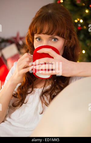 Hübsche Rothaarige auf Couch trinken heißen Schokolade Stockfoto