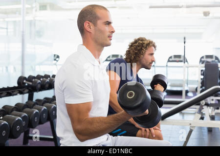 Seitenansicht der Männer, die das Training mit Hanteln im Fitnessstudio Stockfoto